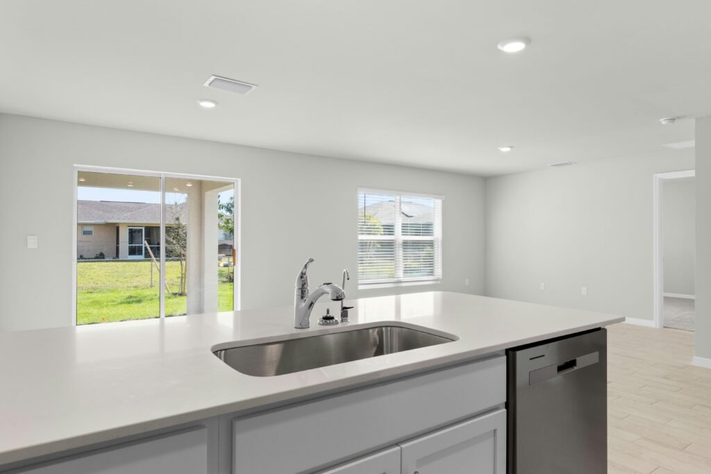 pexels-photo-31606538-31606538 Sleek modern kitchen with island, stainless steel sink, and natural light from large windows.