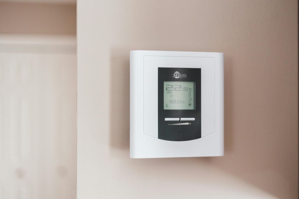 pexels-photo-7616651-7616651 Close-up of a modern digital thermostat mounted on a wall, displaying temperature settings in Celsius.